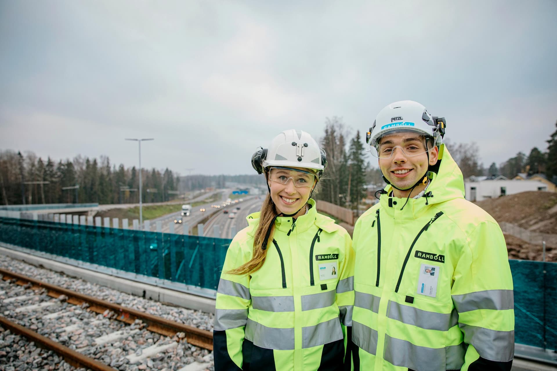 RFI brand picture photoshoot in Espoo, Finland. Taken in October 2021. In the picture two people stand on a bridge on Ring I motorway in Espoo wearing a high-visibility jacket and helmet.